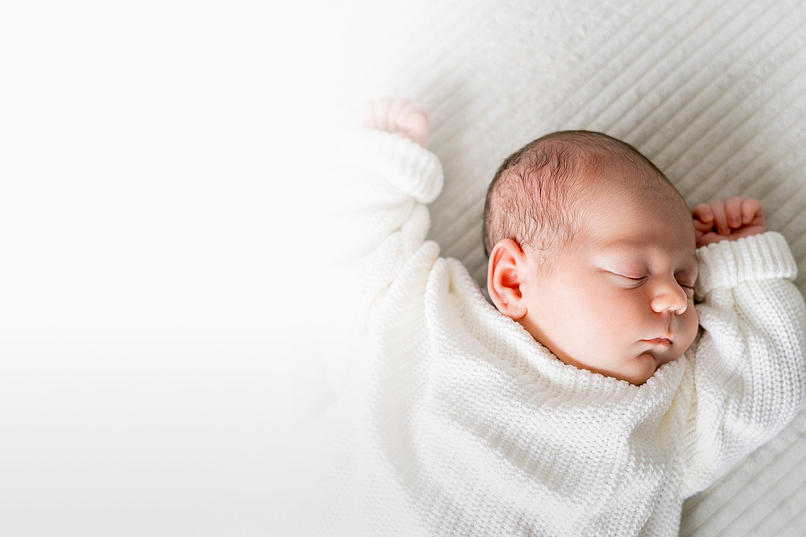 Sleeping baby in a cozy white sweater.