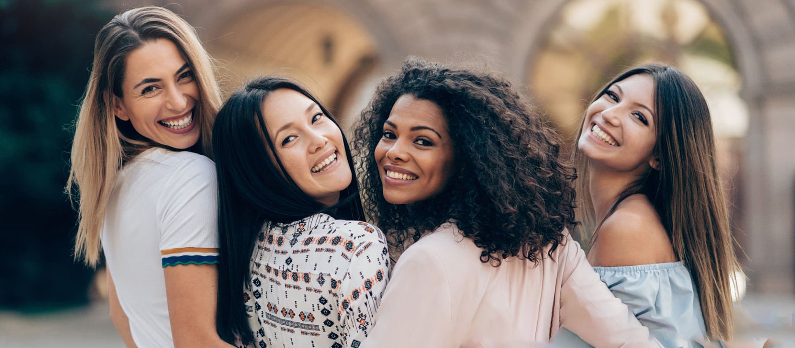 Friends smiling together outdoors, enjoying each other's company.
