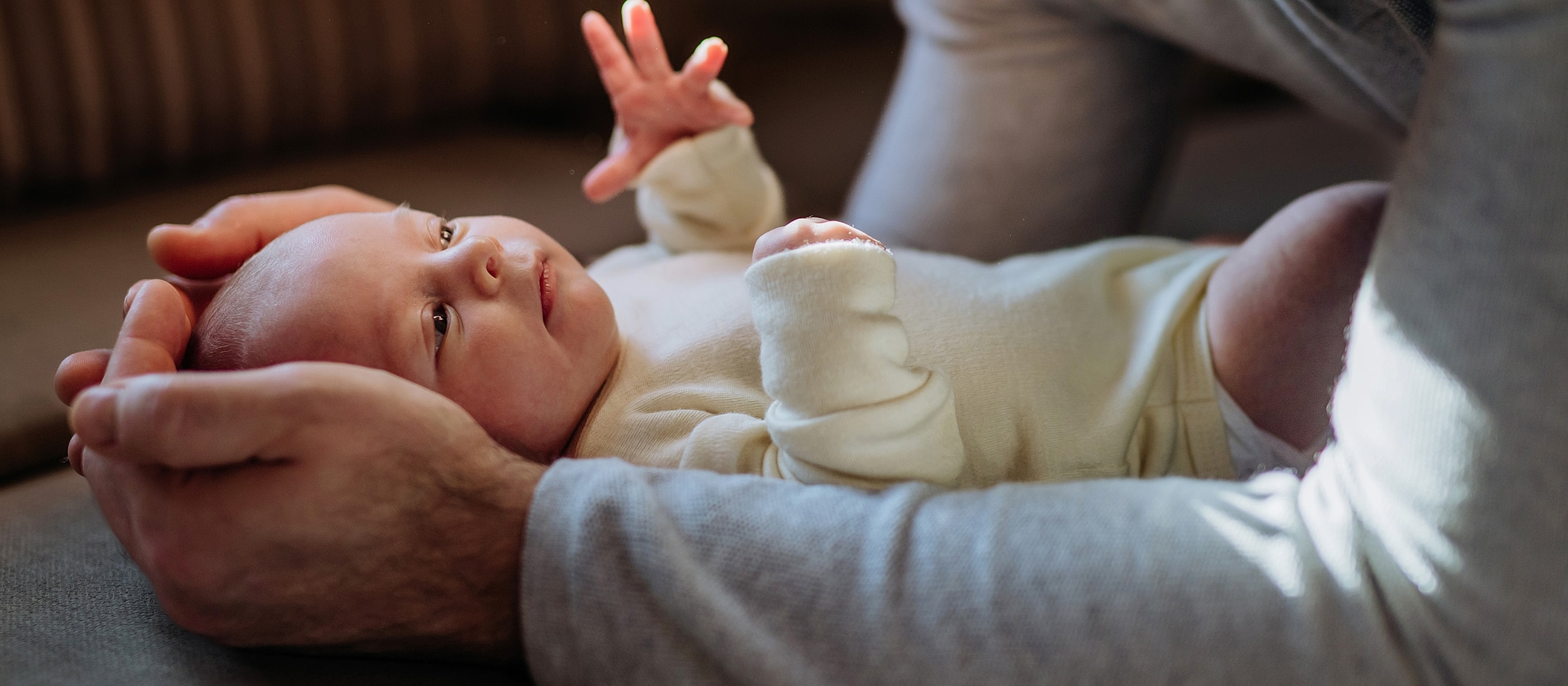 Parent holding a smiling newborn baby gently.