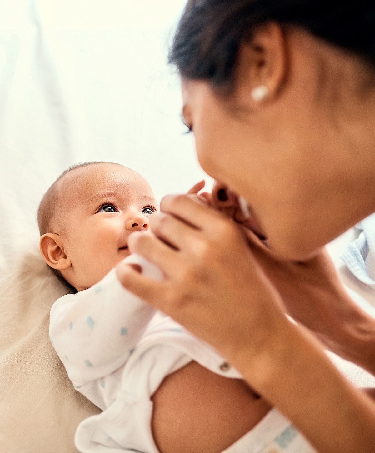 Mother playing with happy baby indoors.