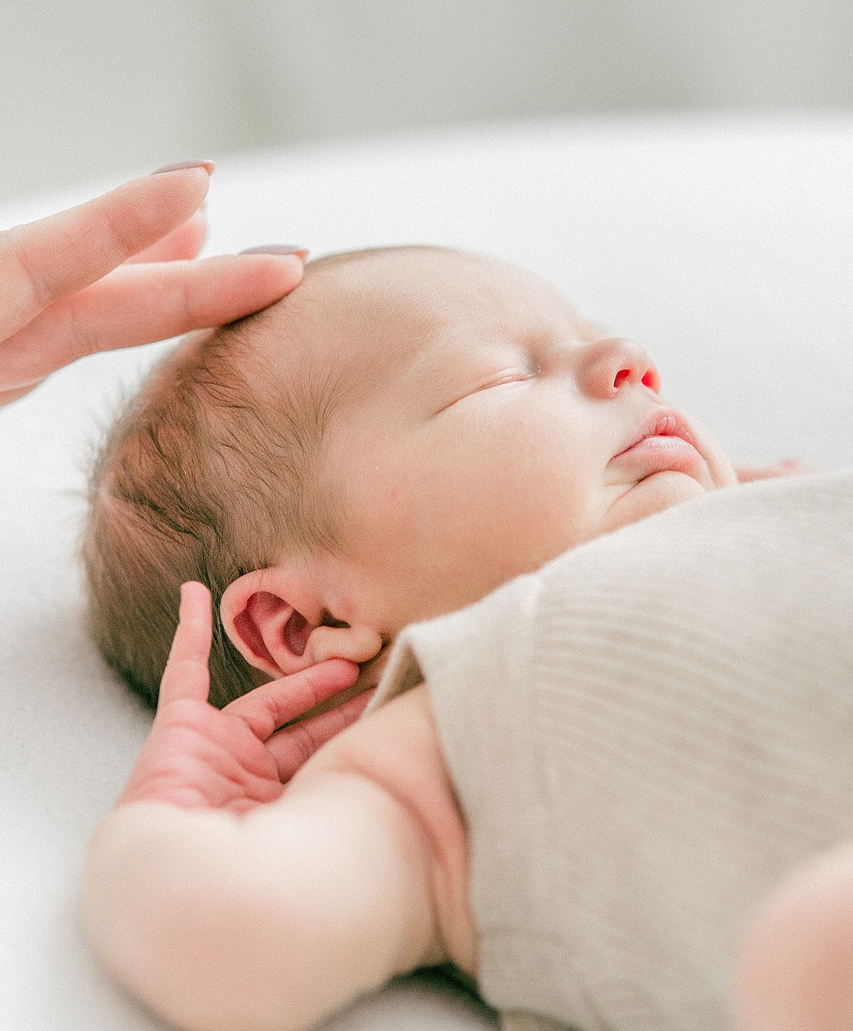 Newborn baby sleeping with gentle hand touch.