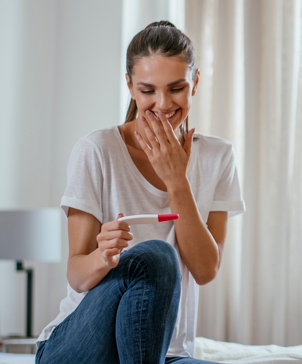 Woman happily checking pregnancy test results at home
