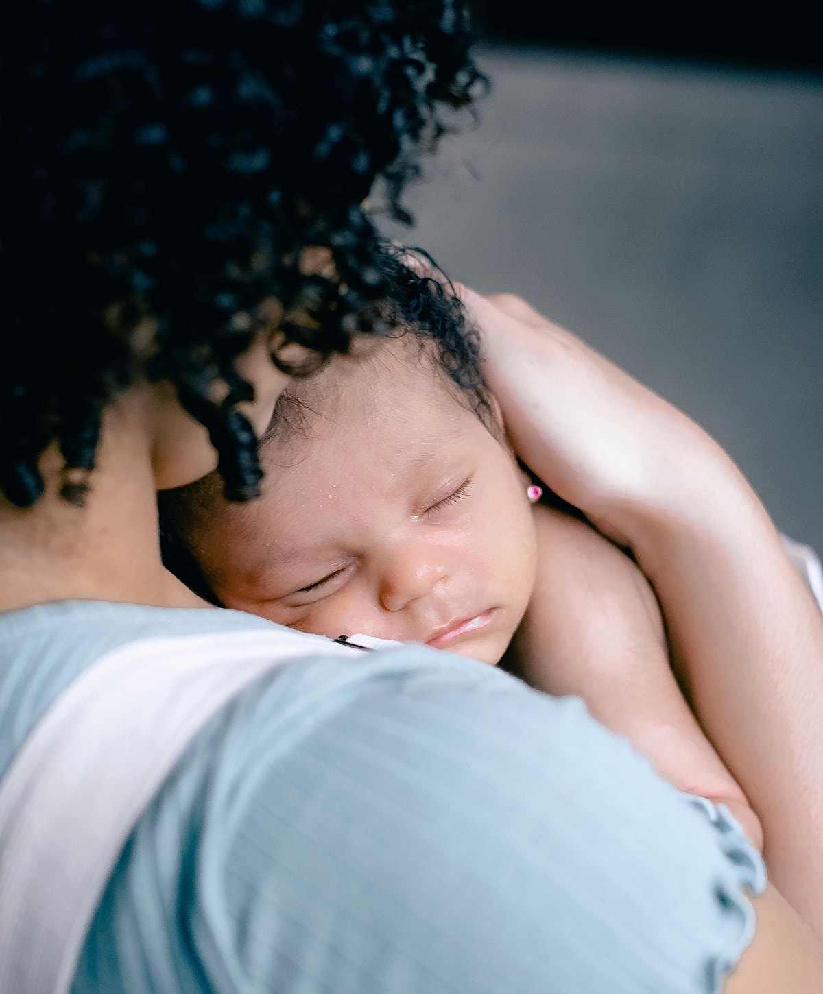 Mother holding sleeping baby close together.