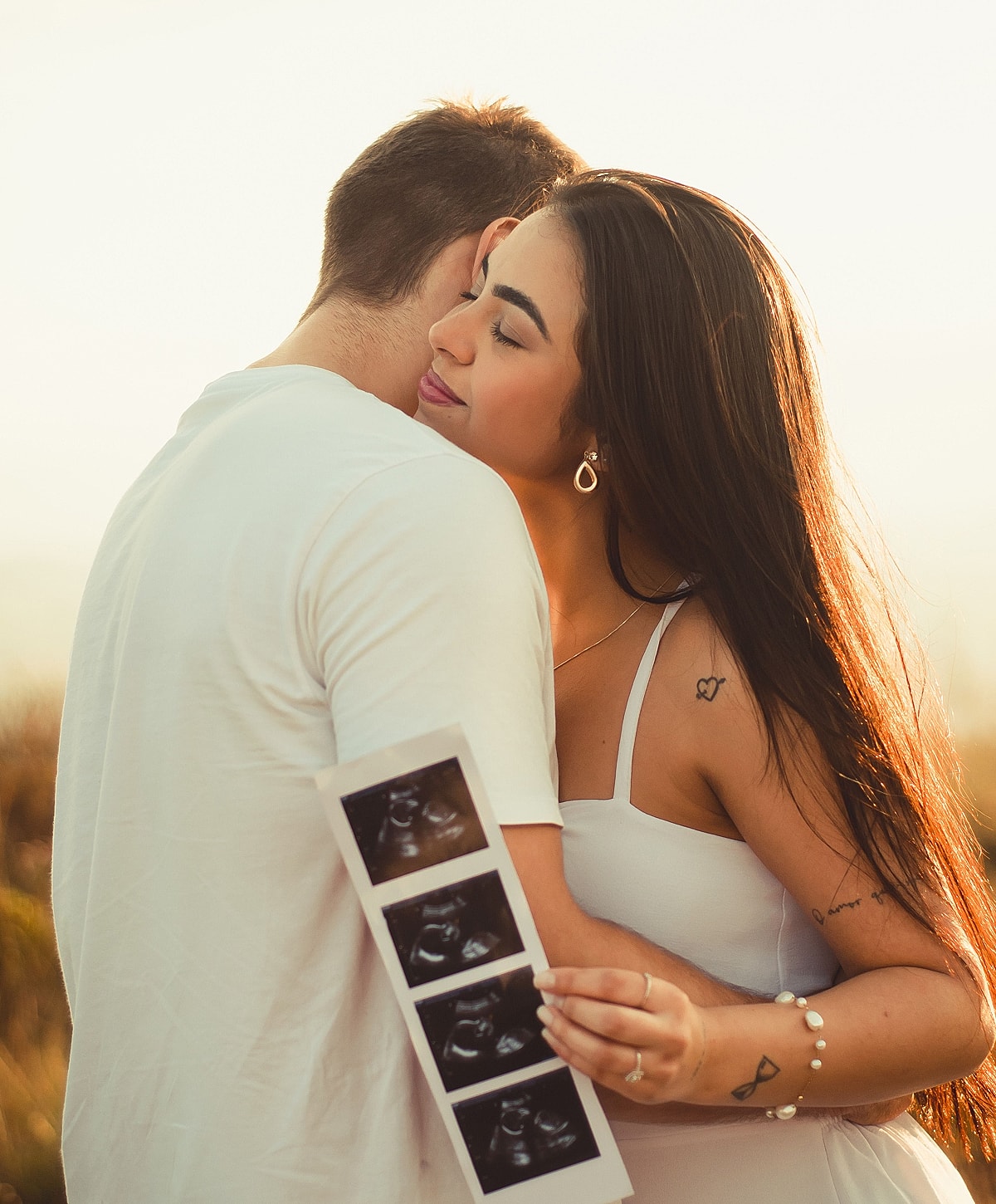 Couple embracing while holding ultrasound photos.