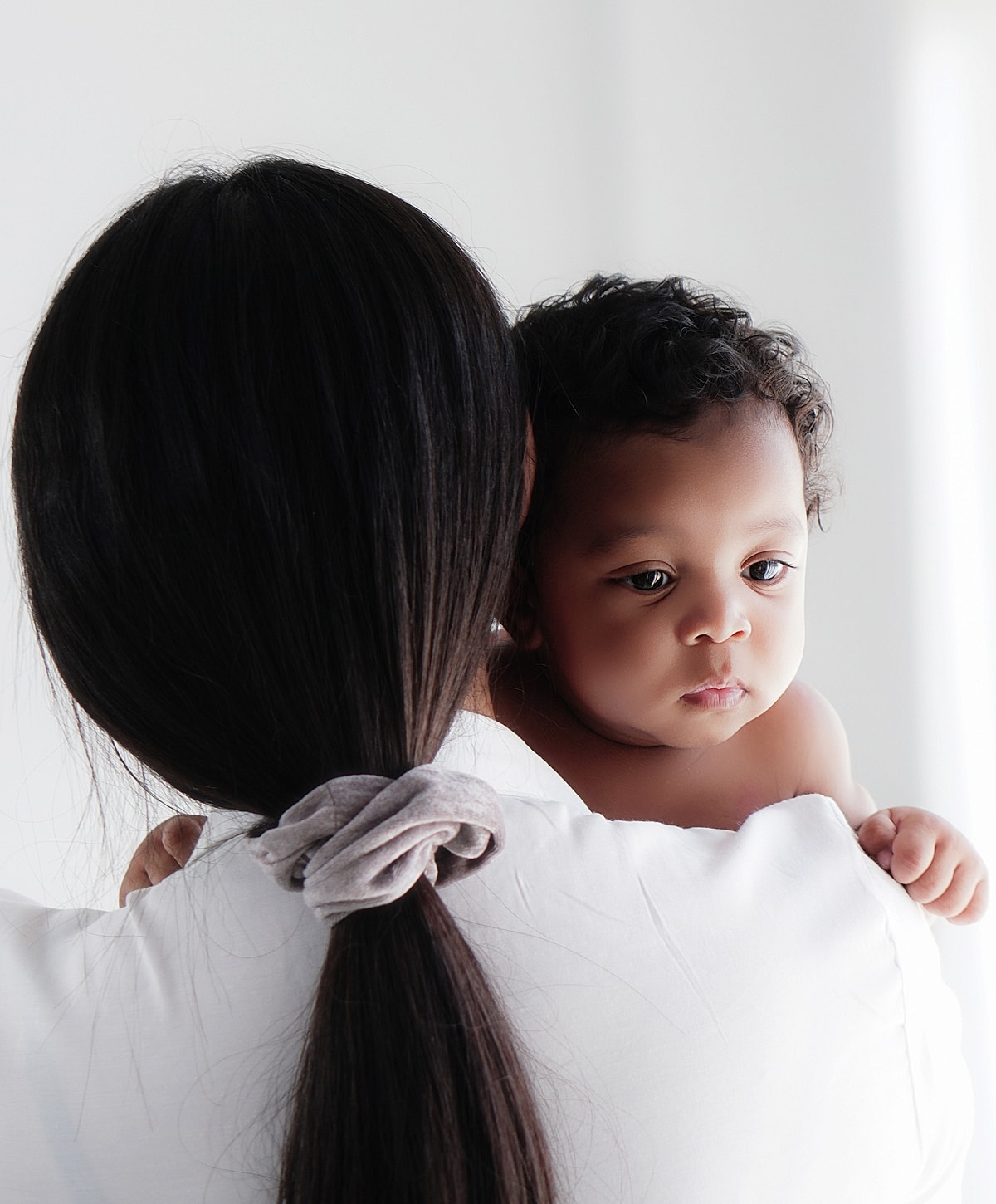 Mother holding baby, both gazing thoughtfully.