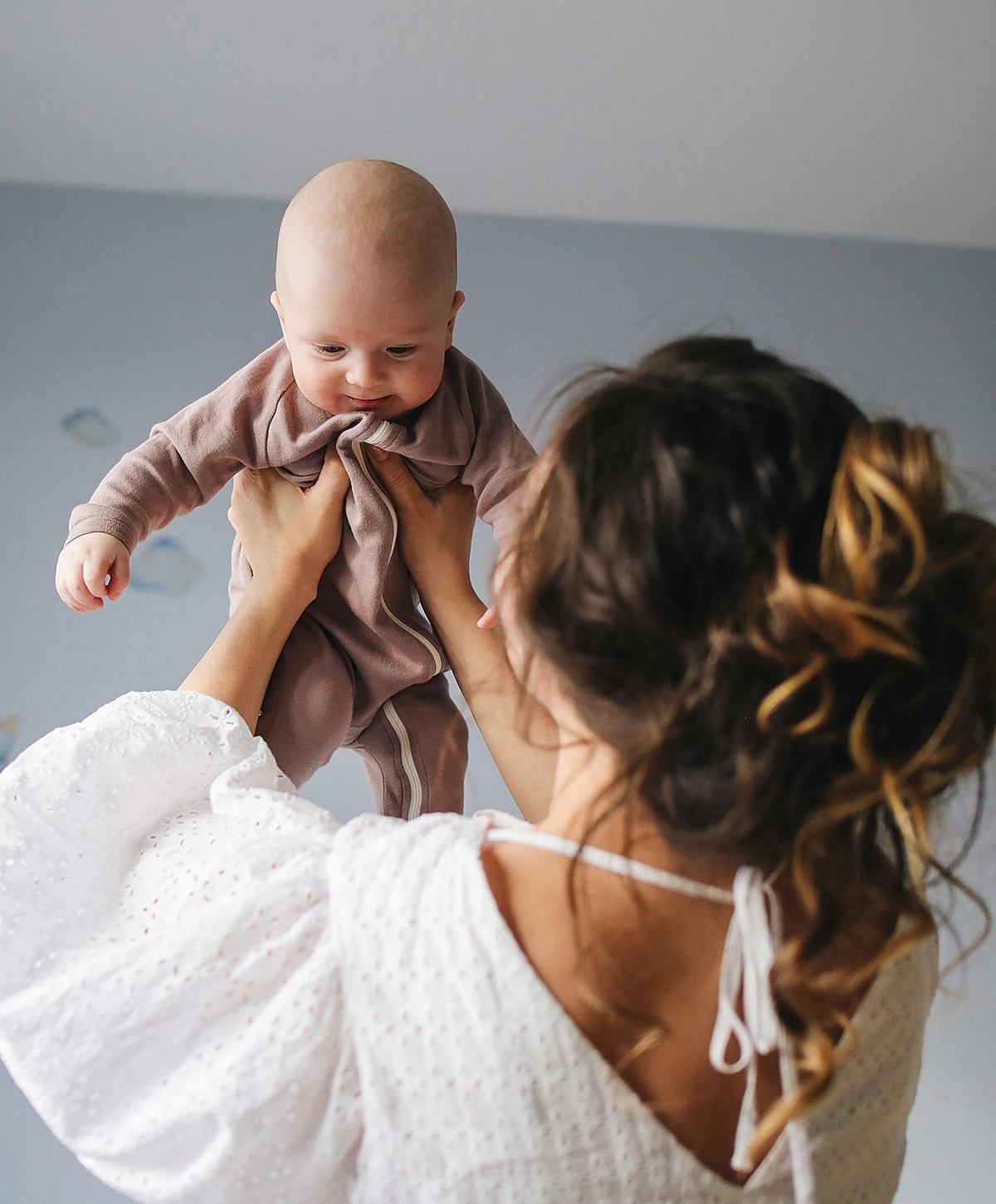 Parent lifting baby in a cozy setting.