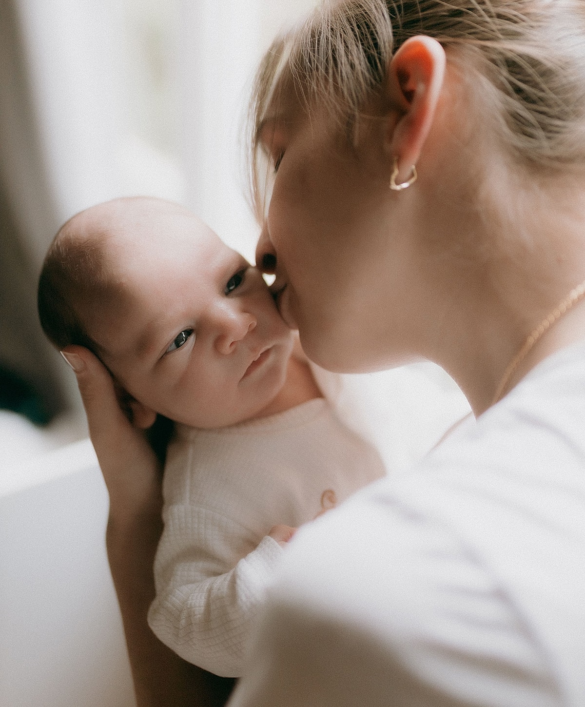Mother kissing her newborn baby lovingly.