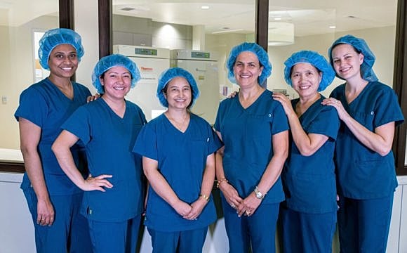 Healthcare professionals smiling in surgical attire.