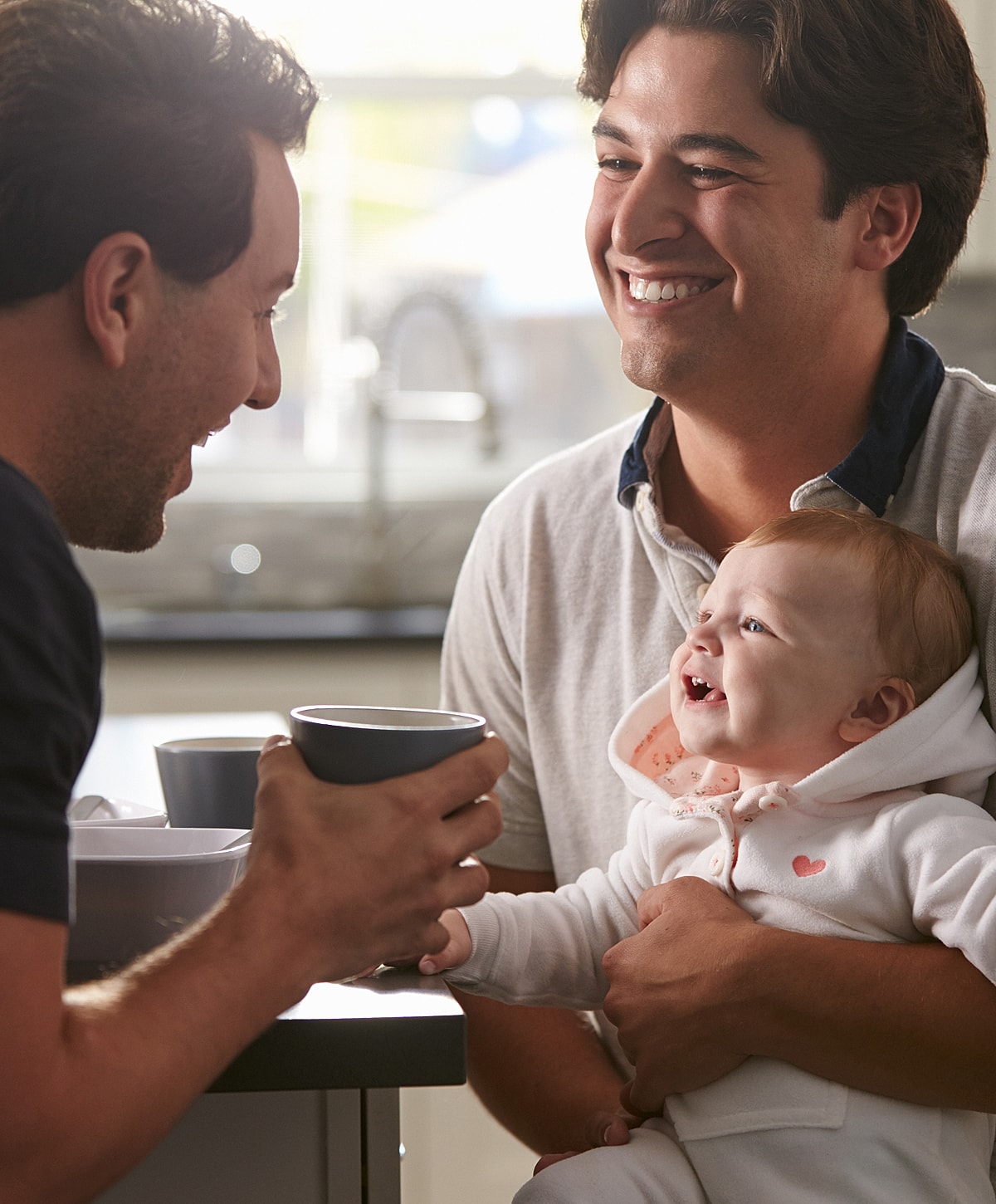 Two men and a baby sharing a joyful moment.