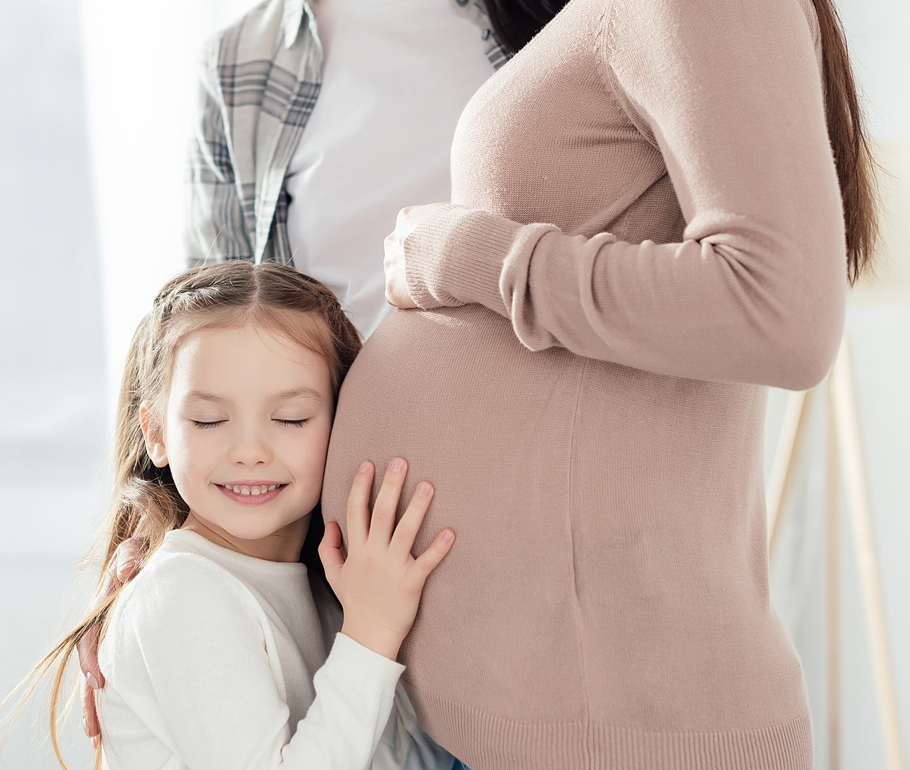 Pregnant mother with daughter smiling together.