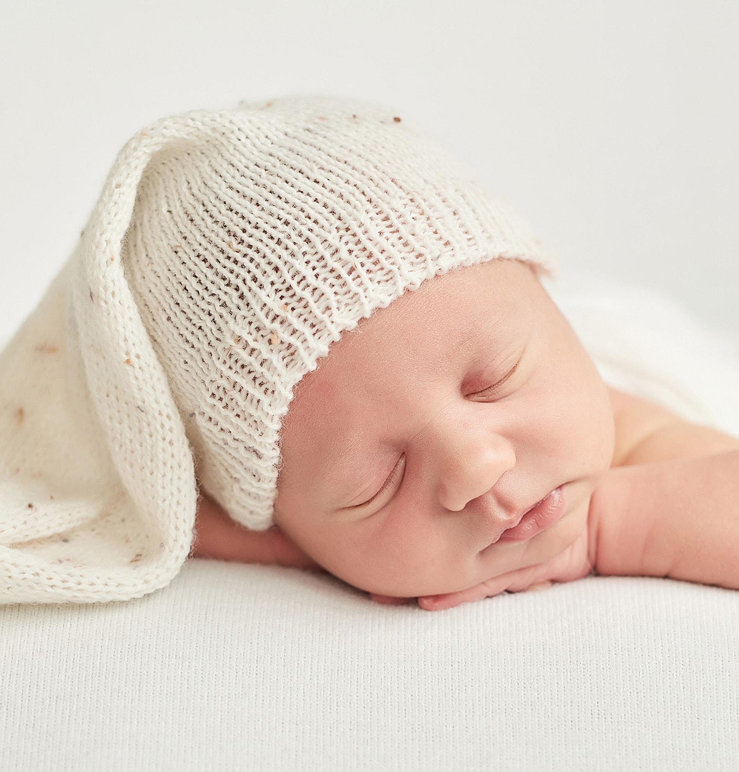 Sleeping newborn wearing a cozy white hat.