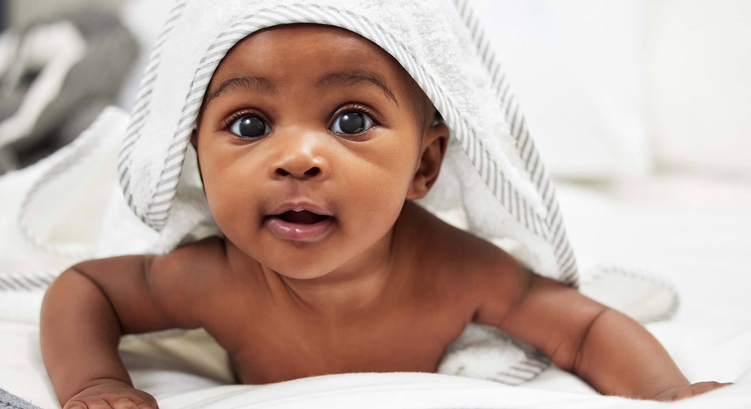 Baby wrapped in a towel, smiling at camera.