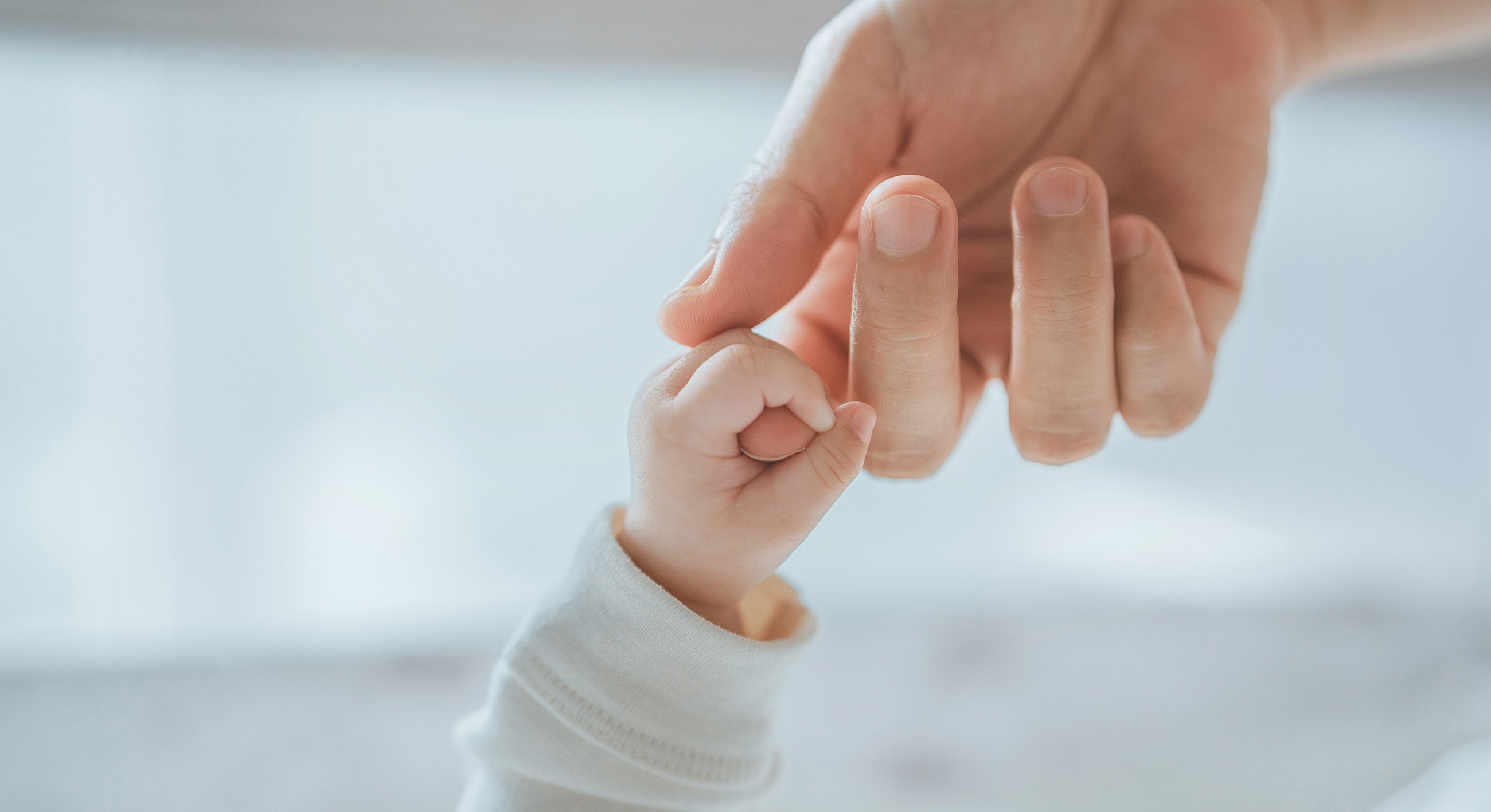 Parent and child hands connecting gently.
