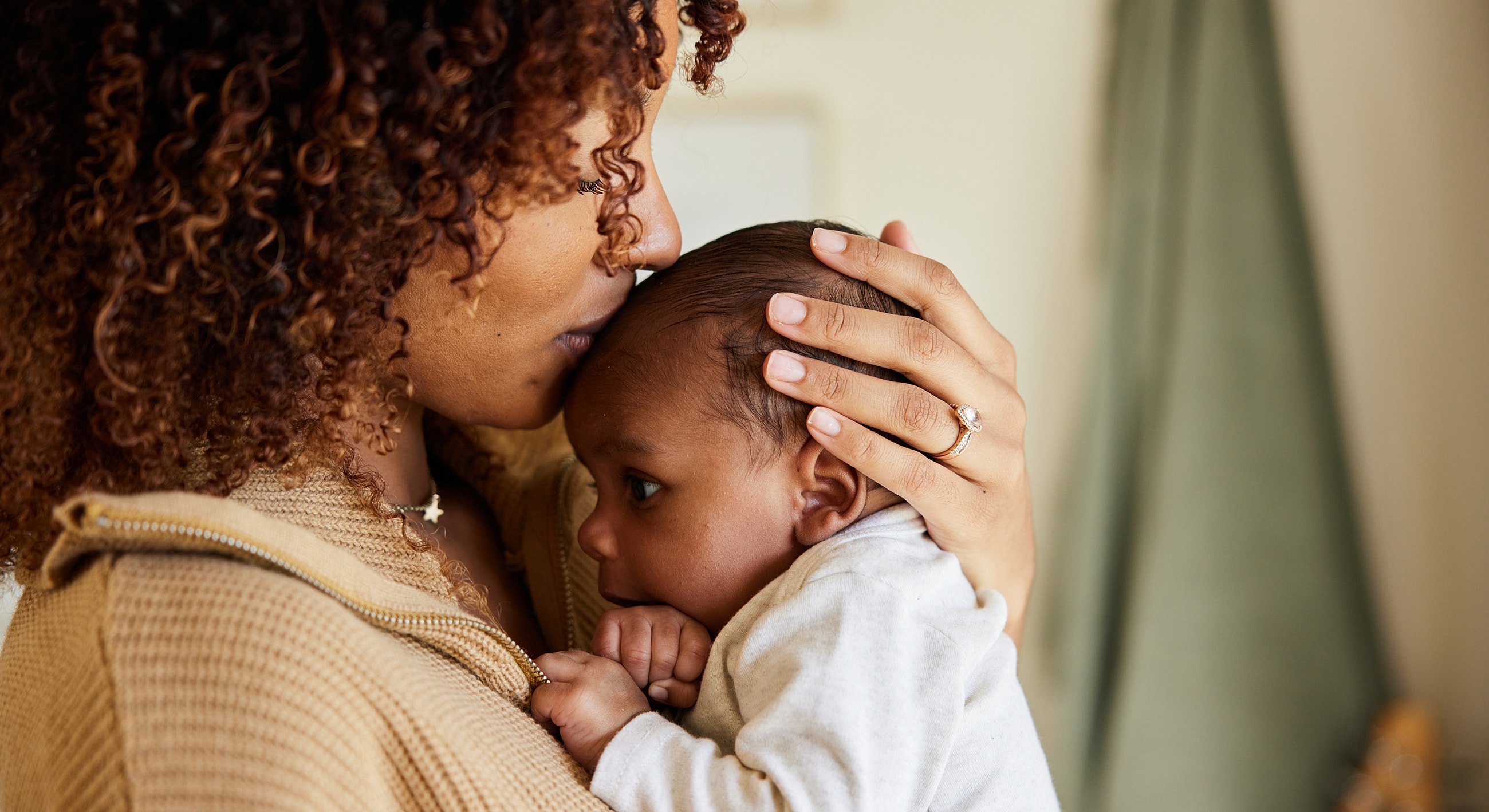 Mother lovingly holds and kisses her baby.