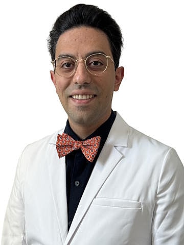 Smiling man in a white coat and bowtie.
