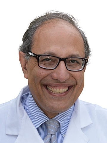 Smiling doctor in white coat with glasses.