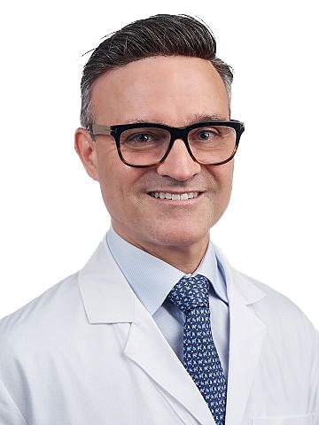Smiling doctor in white coat and glasses.