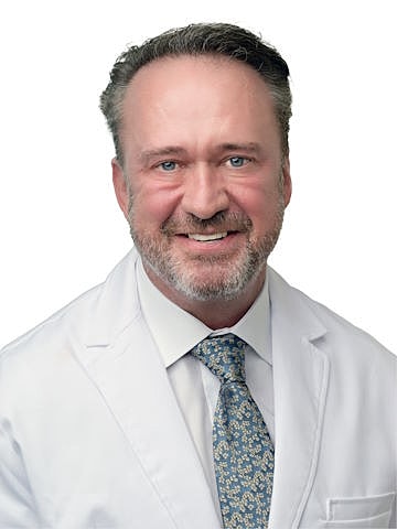 Smiling doctor in white lab coat and tie.