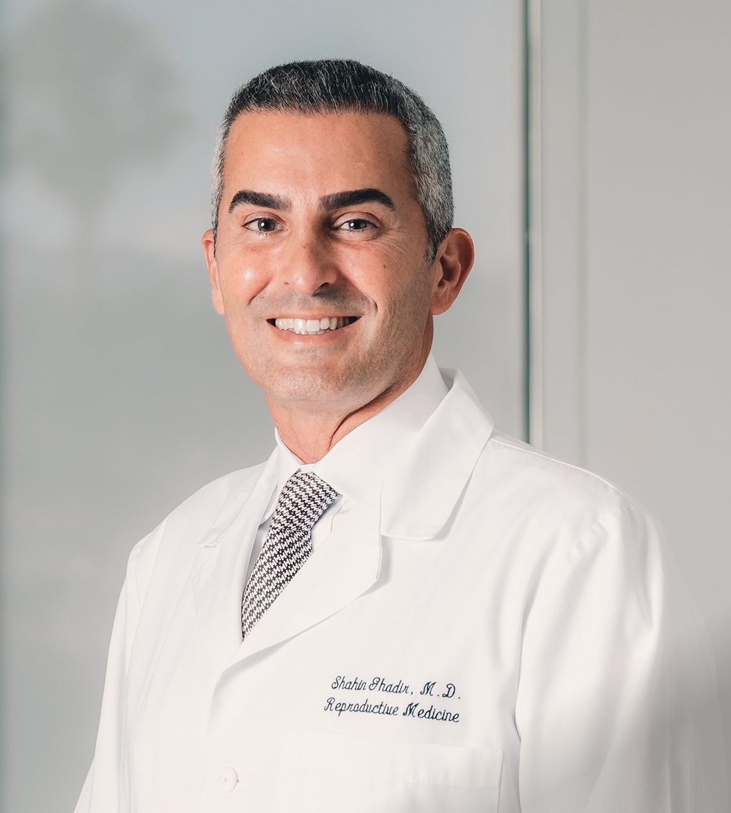 Male doctor in white coat smiling professionally