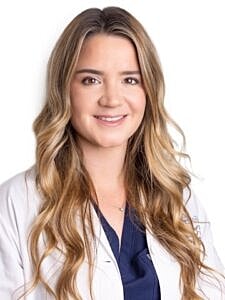 Female doctor in white coat, smiling.