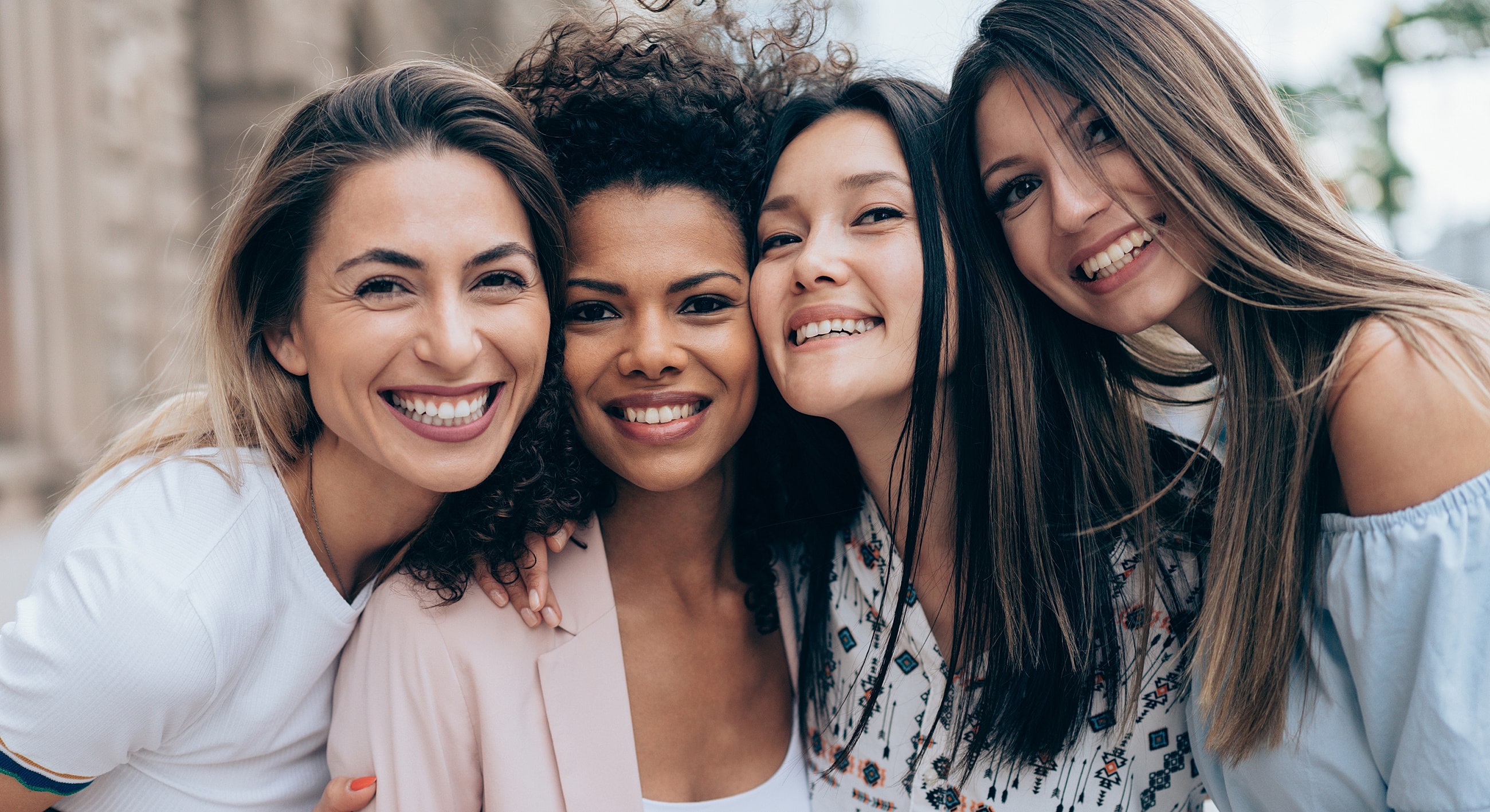 Friends smiling and embracing outdoors.