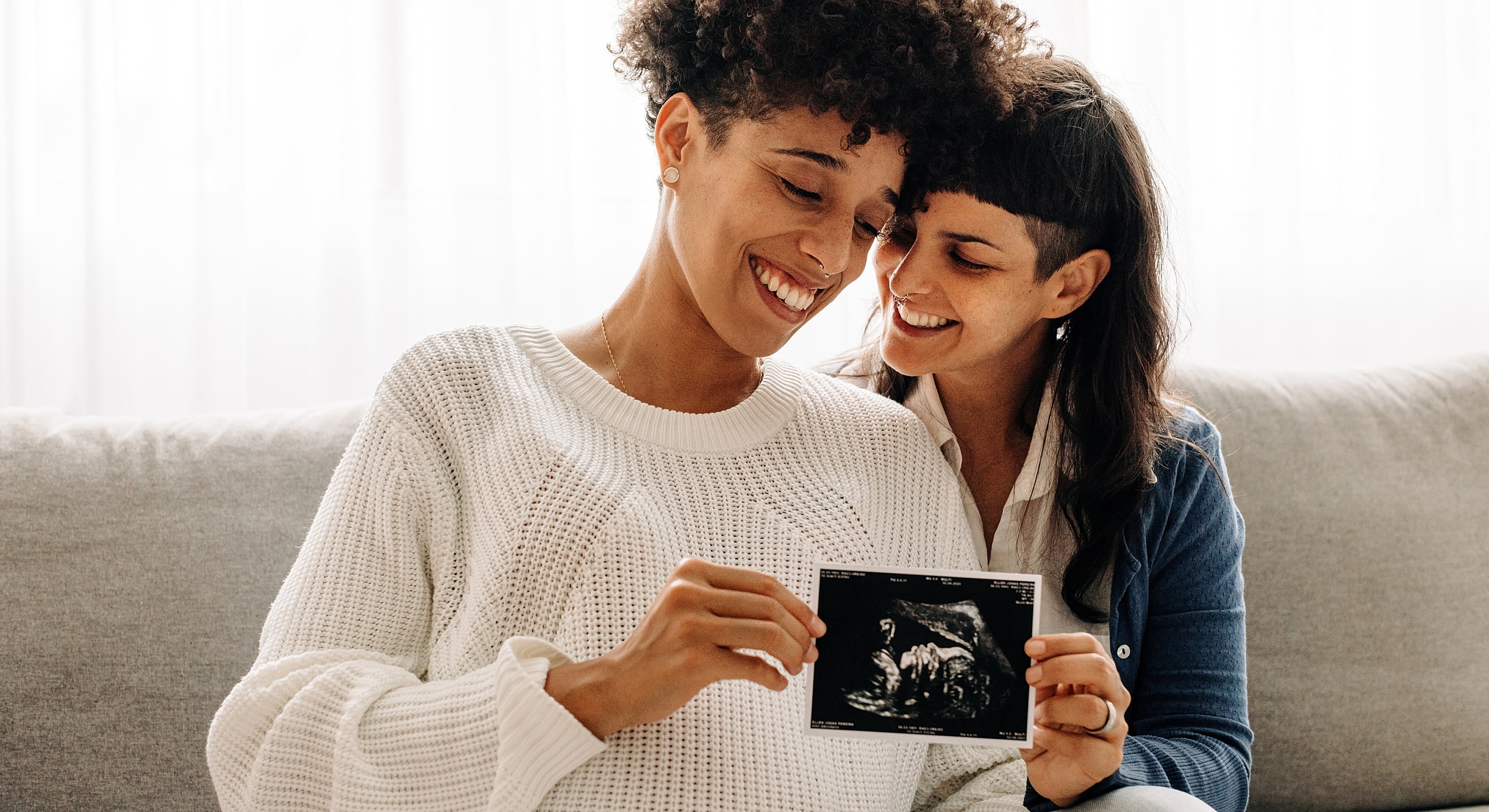 Couple smiling, holding ultrasound photo together.