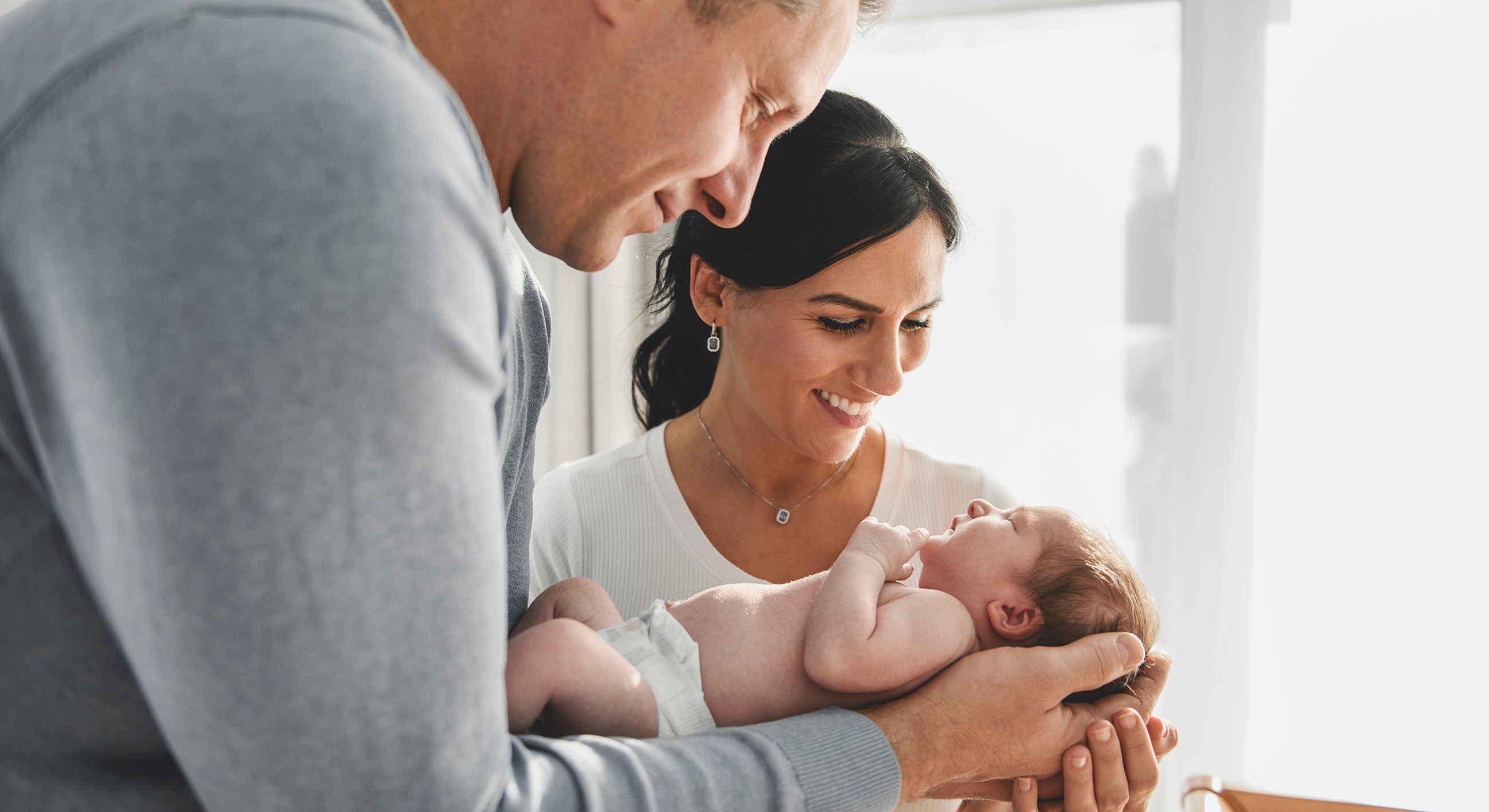 New parents holding their newborn baby together.