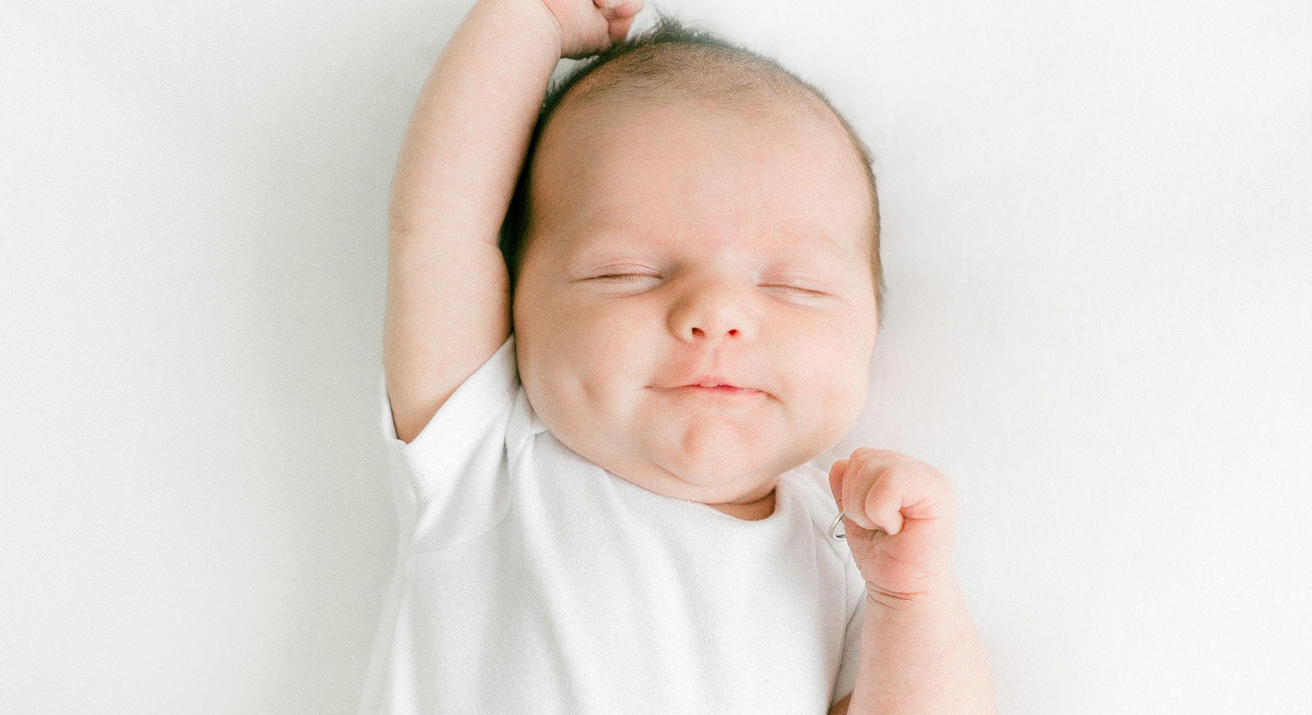 Smiling baby stretching on white background