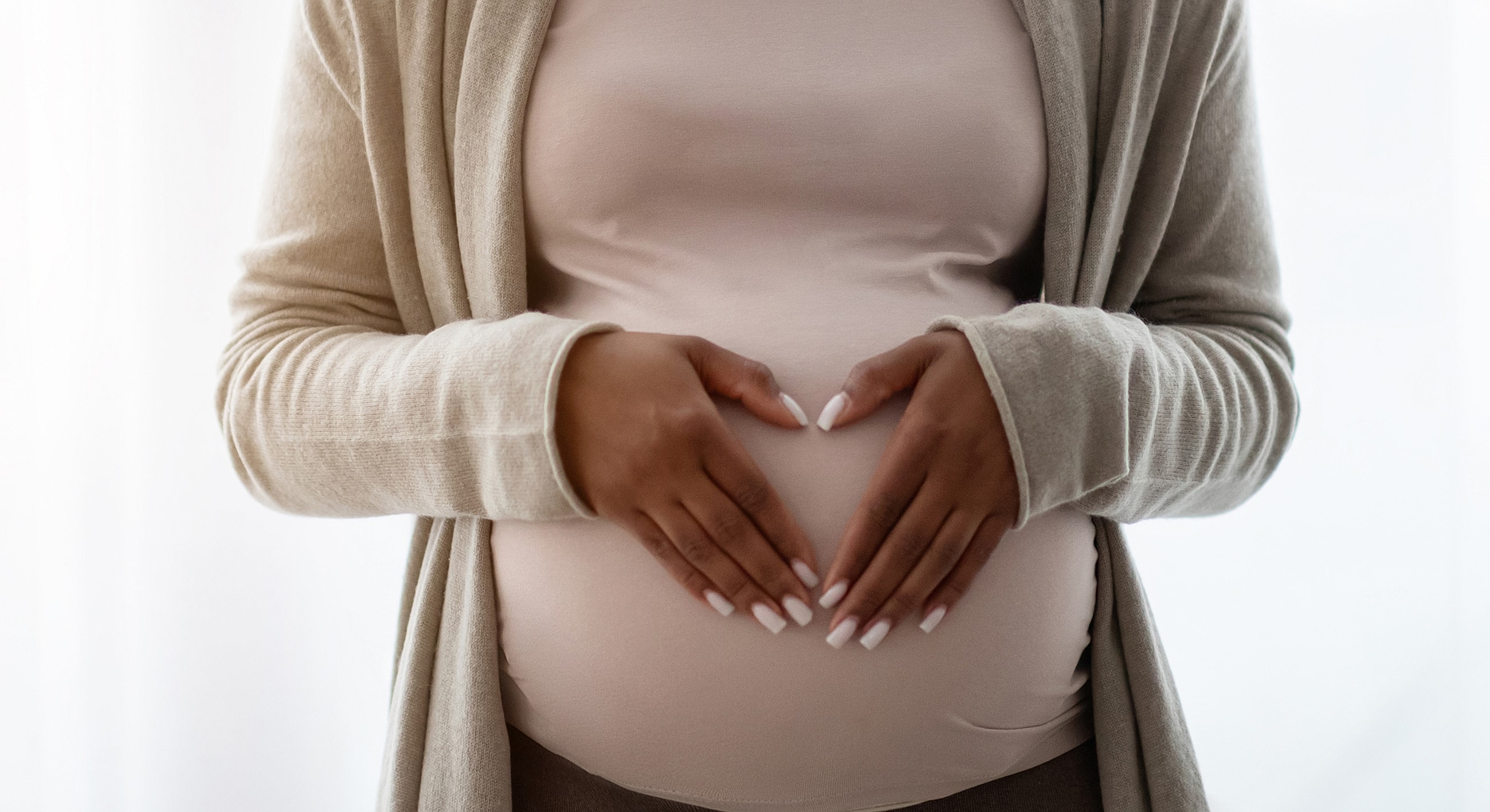 Pregnant woman forming heart with hands on belly