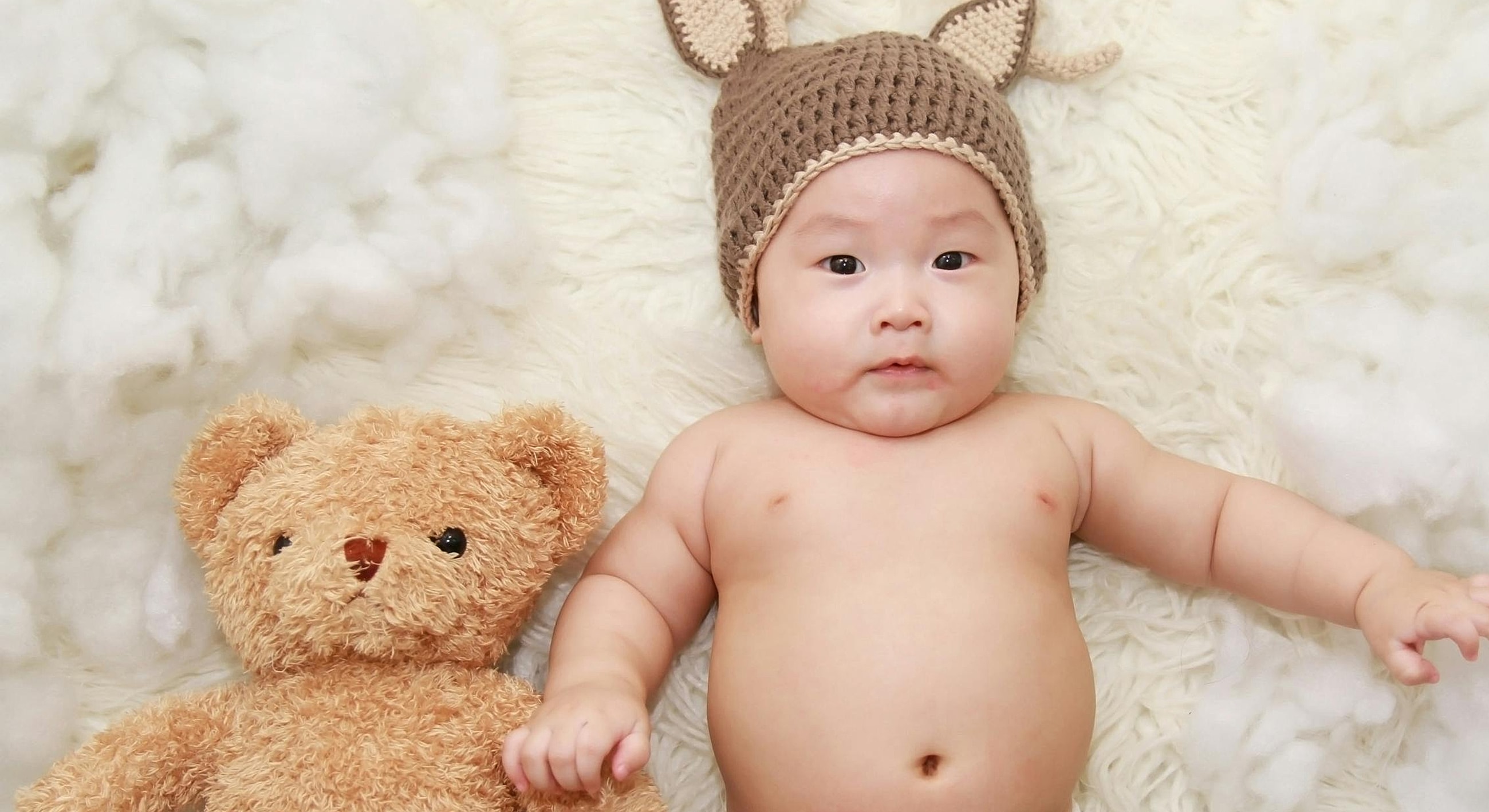 Baby in bunny hat with teddy bear.