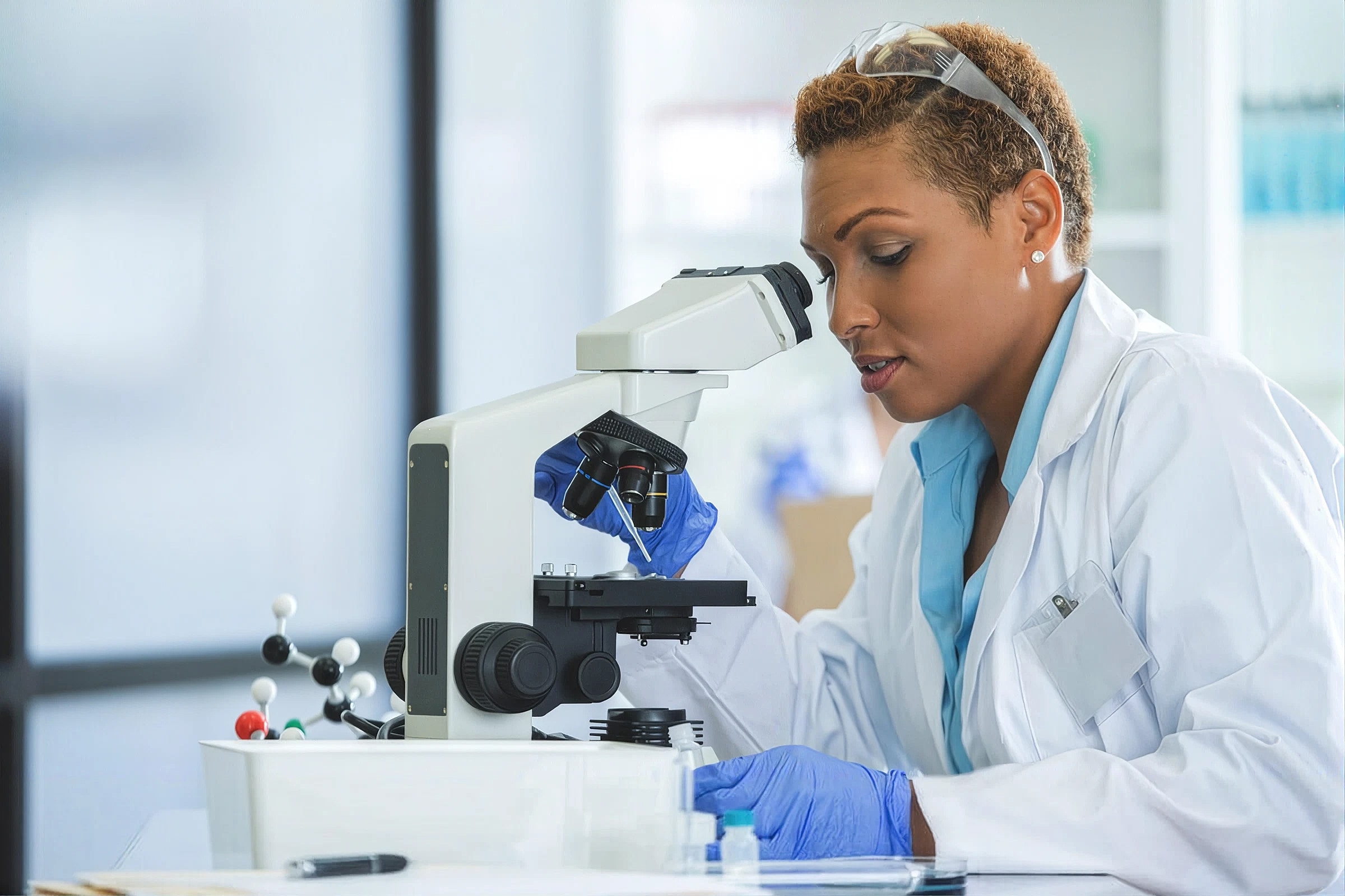 Scientist examining samples through a microscope.