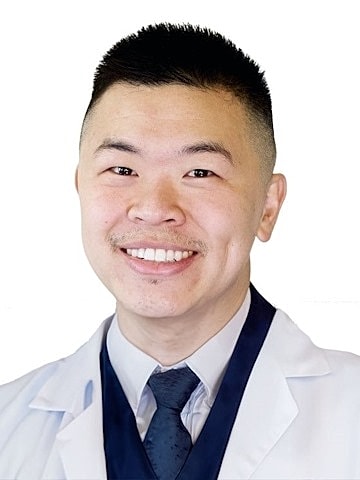 Smiling man in a white lab coat.