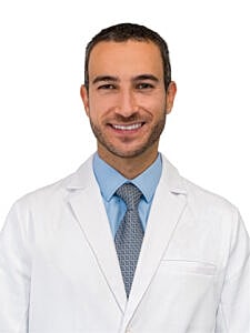 Smiling doctor in white coat and tie.